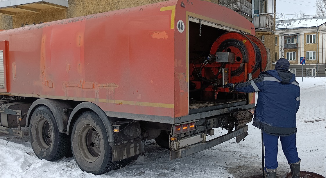 Каналопромывочная машина и работник прочищают засор в канализационной системе в Оле